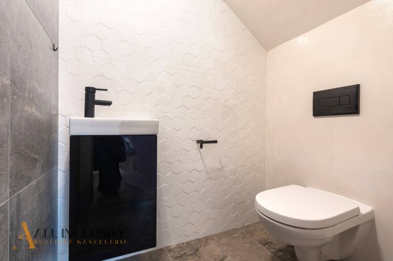 Rezervované 3-izbový byt so záhradou, Šamorín - Kúpeľňa v 3-izbovom byte s bielym obkladom a čiernym umývadlom, šesťhranné dlaždice.