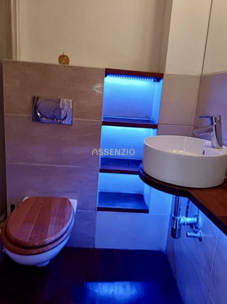 – PRENAJOM – 3 IZBOVÝ BYT – STARE MESTO  - Kúpeľňa v 3-izbovom byte so závesným WC, umývadlom, podsvietenou policou a dreveným dekorom.