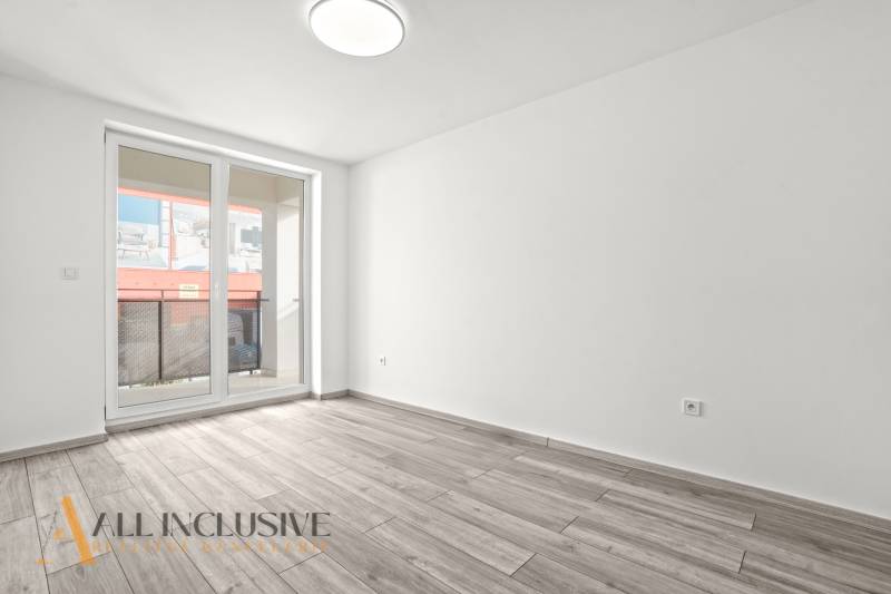 NA PRENÁJOM 3-IZB BYT S BALKÓNOM A ZÁHRADOU,DUN.STREDA - Priestranná miestnosť s podlahou s dreveným dekorom a presklenými dverami v 3-izbovom byte.