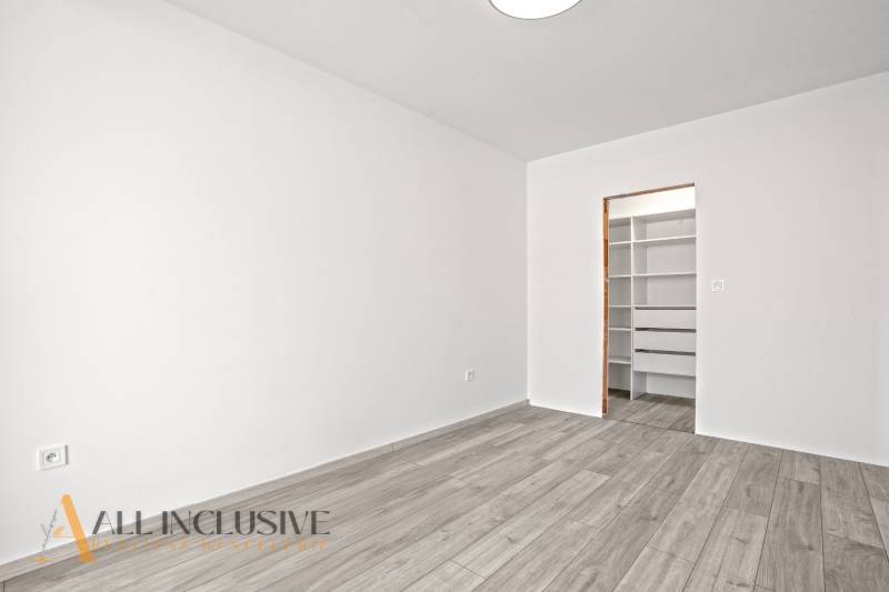 NA PRENÁJOM 3-IZB BYT S BALKÓNOM A ZÁHRADOU,DUN.STREDA - Biela miestnosť s podlahou s dreveným dekorom a otvoreným šatníkom v 3-izbovom byte.