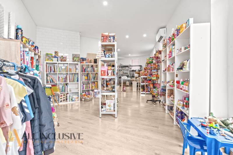 NA PREDAJ NEBYTOVÝ PRIESTOR V DUNAJSKEJ STREDE - Interiér obchodných priestorov s hračkami, knihami a odevmi na podlahe s dreveným dekorom.