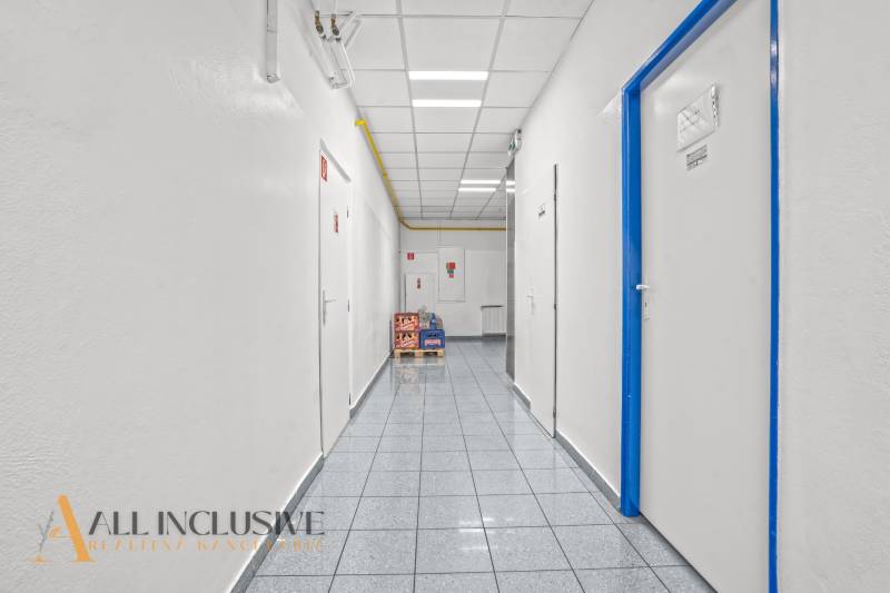 NA PRENÁJOM OBCHODNÝ PRIESTOR V DUNAJSKEJ STREDE - Koridor v obchodných priestoroch s bielymi stenami a dverami lemovanými modrou.