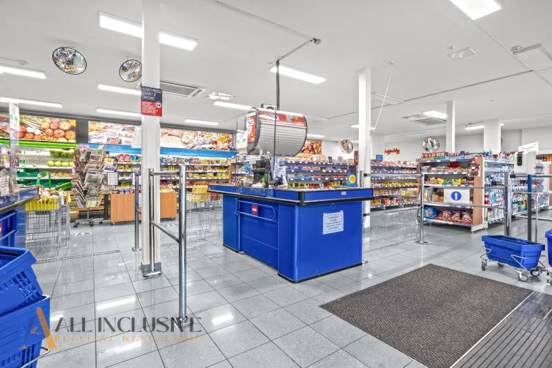 NA PRENÁJOM OBCHODNÝ PRIESTOR V DUNAJSKEJ STREDE - Interiér obchodných priestorov s rôznymi produktmi, pokladňou a nákupnými košíkmi.