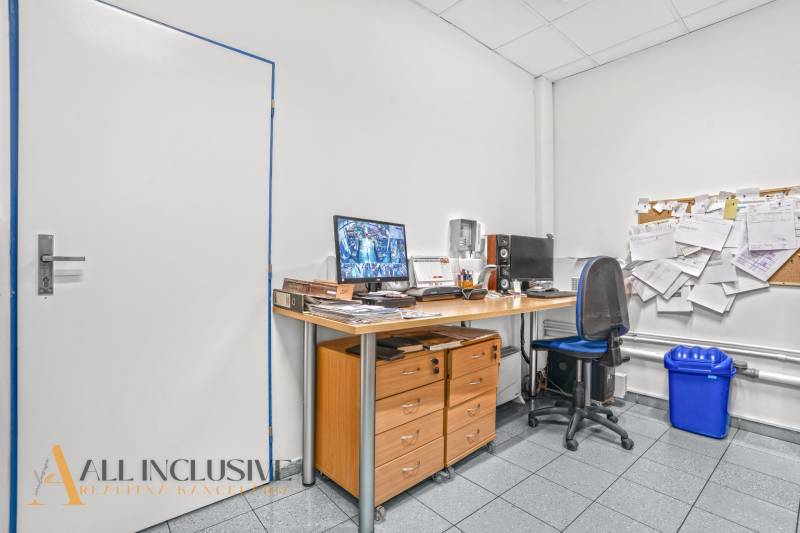 NA PRENÁJOM OBCHODNÝ PRIESTOR V DUNAJSKEJ STREDE - Kancelária s dreveným stolom, modrou stoličkou, nástennou nástenkou a počítačovým vybavením.