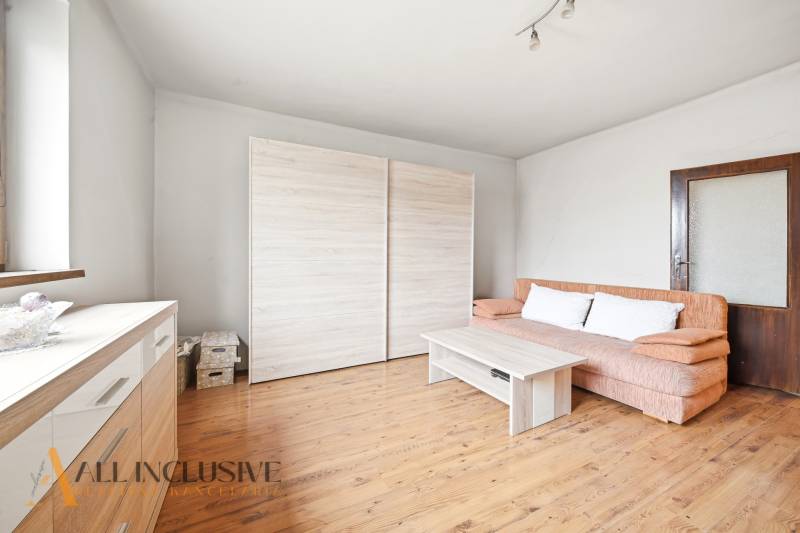 Na predaj 3-izbový rodinný dom, Topoľníky - Obývacia izba v rodinnom dome s podlahou s dreveným dekorom, pohovkou a skriňou.