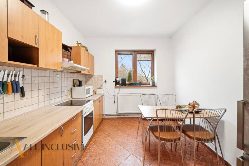 Na predaj 3-izbový rodinný dom, Topoľníky - Kuchyňa v rodinnom dome s drevenými skrinkami, stolom a dlažbou na podlahe.