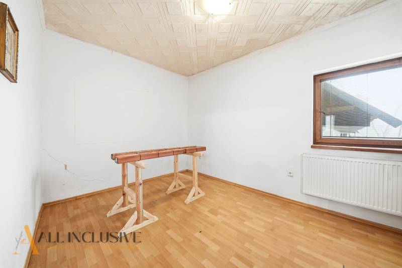 Na predaj 3-izbový rodinný dom, Topoľníky - Priestranná miestnosť v rodinnom dome s podlahou s dreveným dekorom a jednoduchým stolom.
