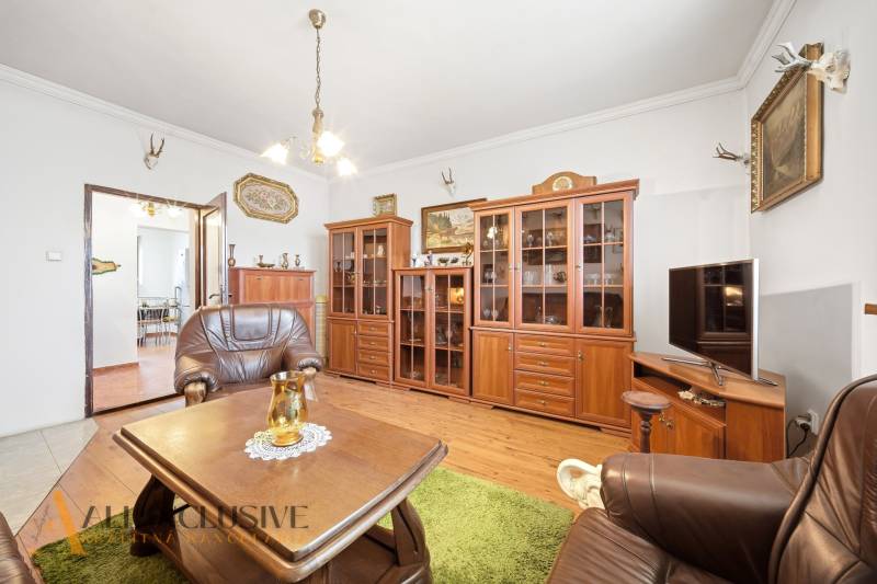 Na predaj 3-izbový rodinný dom, Topoľníky - Obývacia izba v rodinnom dome so skrinkami, kreslami a podlahou s dreveným dekorom.