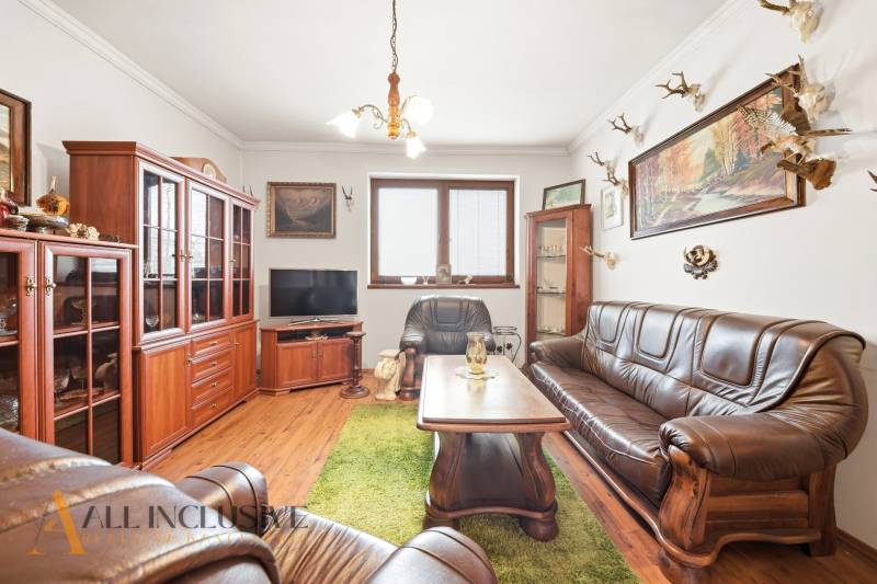 Na predaj 3-izbový rodinný dom, Topoľníky - Obývacia izba v rodinnom dome s koženou sedačkou a podlahou s dreveným dekorom.