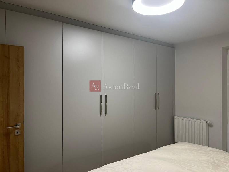 EXKLUZÍVNE-PREDAJ 3-IZBOVÝ BYT POPRAD, širšie centrum 80 m2 s gar.st. - V 3-izbovom byte sú šatníkové skrine s bielymi posuvnými dverami a posteľou.