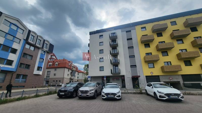 EXKLUZÍVNE-PREDAJ 3-IZBOVÝ BYT POPRAD, širšie centrum 80 m2 s gar.st. - Bytovky na Hviezdoslavovej ulici v Poprade s parkoviskom a zatiahnutou oblohou.