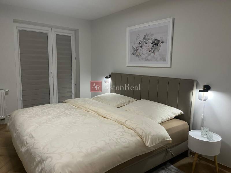 EXKLUZÍVNE-PREDAJ 3-IZBOVÝ BYT POPRAD, širšie centrum 80 m2 s gar.st. - Spálňa v 3-izbovom byte so svetlou posteľou a jemným dekórom na stene.