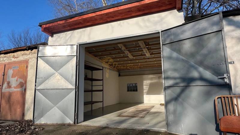 Zrekonštruovaná veľká garáž na ul. Agátova, Dúbravka s pozemkom - Otvretá garáž na Agátovej v Bratislave - Dúbravke s jednoduchým interiérom a regálom.