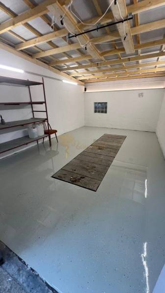 Zrekonštruovaná veľká garáž na ul. Agátova, Dúbravka s pozemkom - Garáže s regálmi a svetlými stenami, podlaha s jamou na opravu vozidiel.