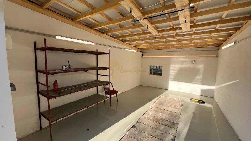 Zrekonštruovaná veľká garáž na ul. Agátova, Dúbravka s pozemkom - Interiér garáže s podlahou s dreveným dekorom a regálom v Bratislave na Agátovej ulici.