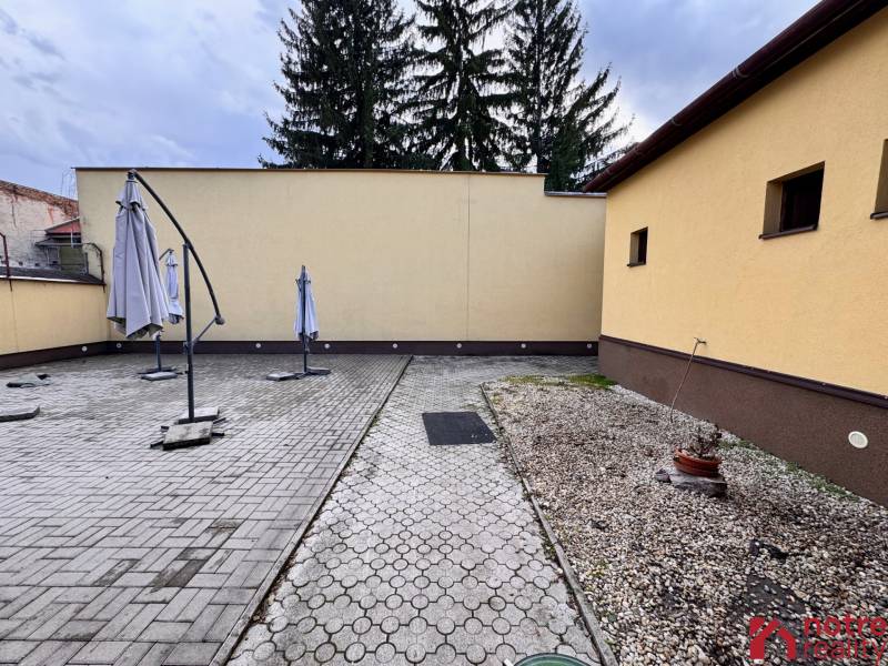 Podnikateľský objekt na prenájom v Lučenci - Plocha gastro priestoru v centre Lučenca so slnečníkmi a dlažbou.