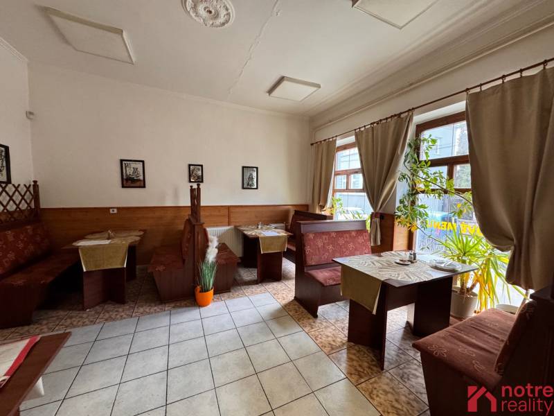 Podnikateľský objekt na prenájom v Lučenci - Drevený dekor sedenia v gastro priestoroch s rastlinami a dekoráciami na stenách.