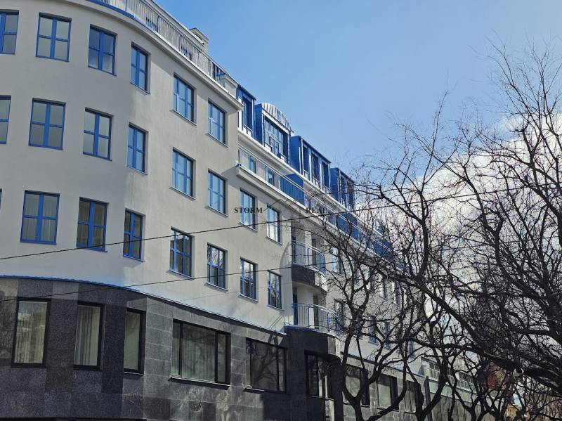 VÝNIMOČNÝ APARTMÁN priamo v centra mesta - projekt UNO Poštová - Budova v Bratislave - Starom Meste na Poštovej ulici so stromami v popredí.