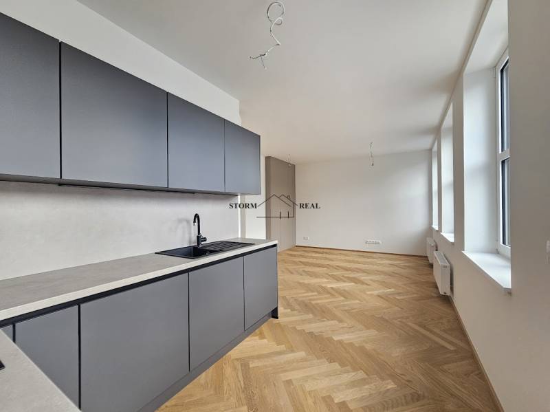 VÝNIMOČNÝ APARTMÁN priamo v centra mesta - projekt UNO Poštová - Kuchyňa v 1-izbovom byte s podlahou s dreveným dekorom a veľkými oknami.