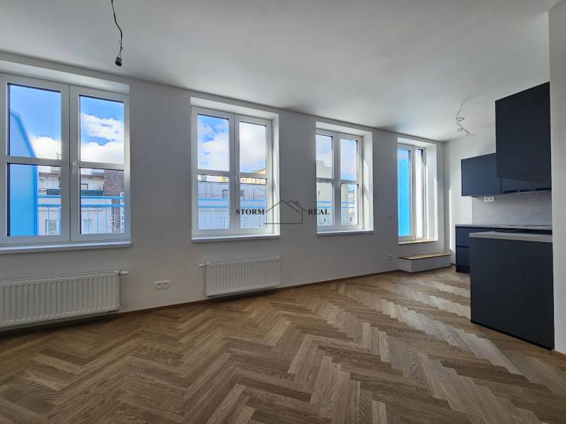 VÝNIMOČNÝ APARTMÁN priamo v centra mesta - projekt UNO Poštová - 1-izbový byt s podlahou s dreveným dekorom a čiernou kuchynskou linkou.