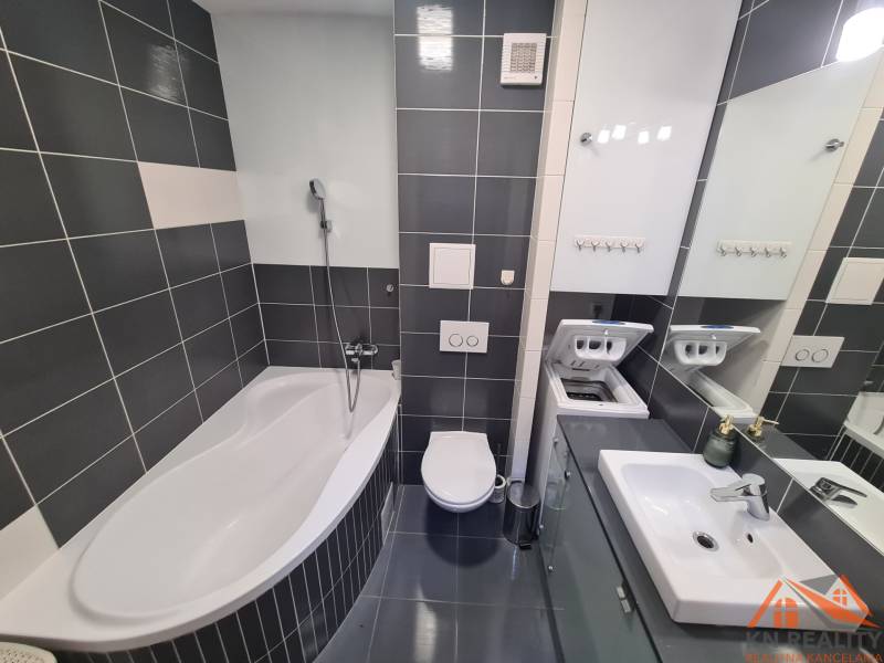 Reprezentatívny 2 izb.byt na prenájom SOHO TOWER Komárno ! - Kúpeľňa v 2-izbovom byte s vaňou, práčkou, umývadlom a tmavými obkladačkami.