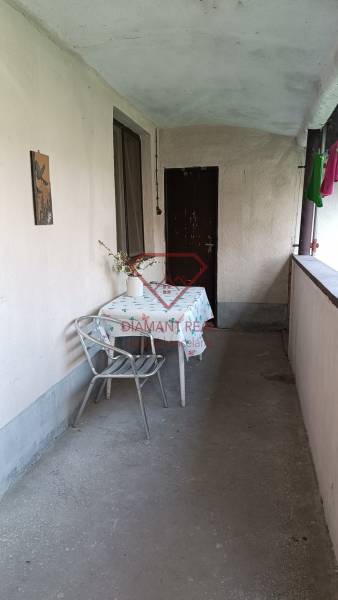 Na predaj RD na bývanie alebo investičná príležitosť Horné Saliby - Zastrešená terasa rodinného domu, stôl so stoličkou, váza s kvetmi, obytný priestor.