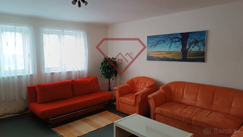 Na predaj RD na bývanie alebo investičná príležitosť Horné Saliby - Obývacia izba v rodinnom dome s oranžovou sedačkou, kreslami a obrazom krajiny.