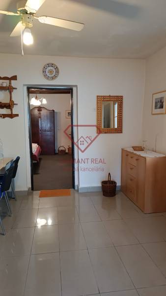 Na predaj RD na bývanie alebo investičná príležitosť Horné Saliby - Interiér rodinného domu s dlažbou, drevenou komodou a stropným ventilátorom.