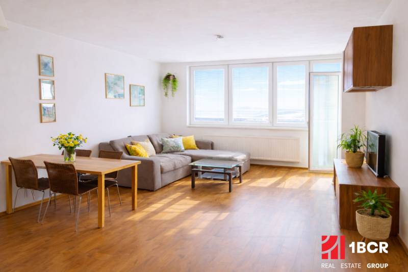 INVESTIČNÉ BÝVANIE V TOP LOKALITE: 2-IZBOVÝ BYT, JÉGÉHO UL, BRATISLAVA - Obývacia izba v 2-izbovom byte s rohovým gaučom a podlahou s dreveným dekorom.