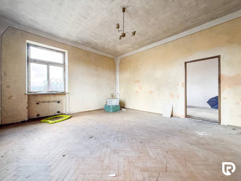 Rodinný dom (bytovka) s pozemkom 554m2, Bobotská Lehota - Izba v rodinnom dome s podlahou s dreveným dekorom a jednoduchým osvetlením.