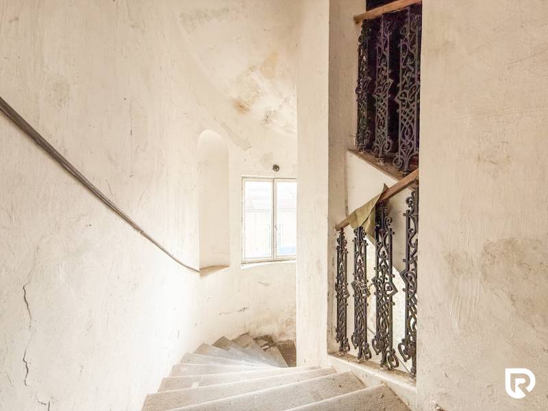 Rodinný dom (bytovka) s pozemkom 554m2, Bobotská Lehota - Schodisko v Rodinnom dome s oknom a ozdobným zábradlím, biela stena s patinou.