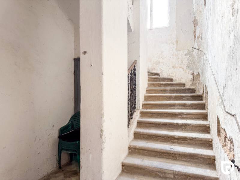 Rodinný dom (bytovka) s pozemkom 554m2, Bobotská Lehota - Schodisko v rodinnom dome so stohom plastových stoličiek. Opotrebované steny.