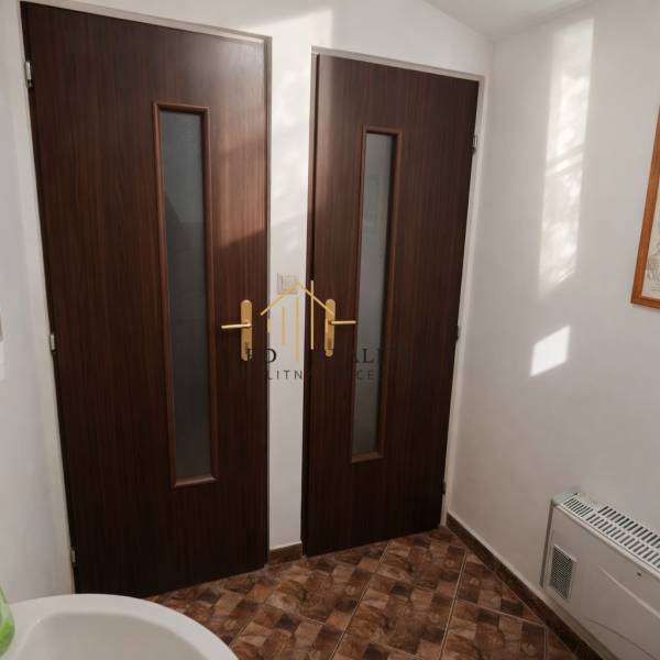 Prenájom gastro priestoru v centre Krupiny - Interiér s dvoma drevenými dverami a podlahou s dreveným dekorom v gastro priestoroch.