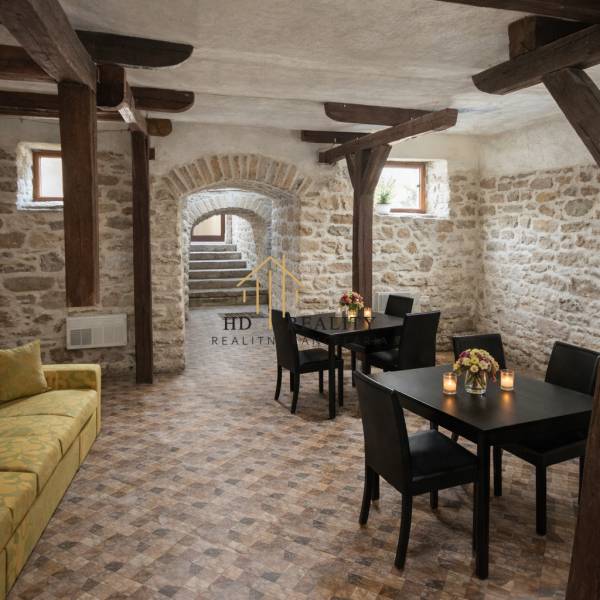 Prenájom gastro priestoru v centre Krupiny - Interiér gastro priestorov s kamennými stenami a podlahou s dreveným dekorom, stoly s kvetmi.