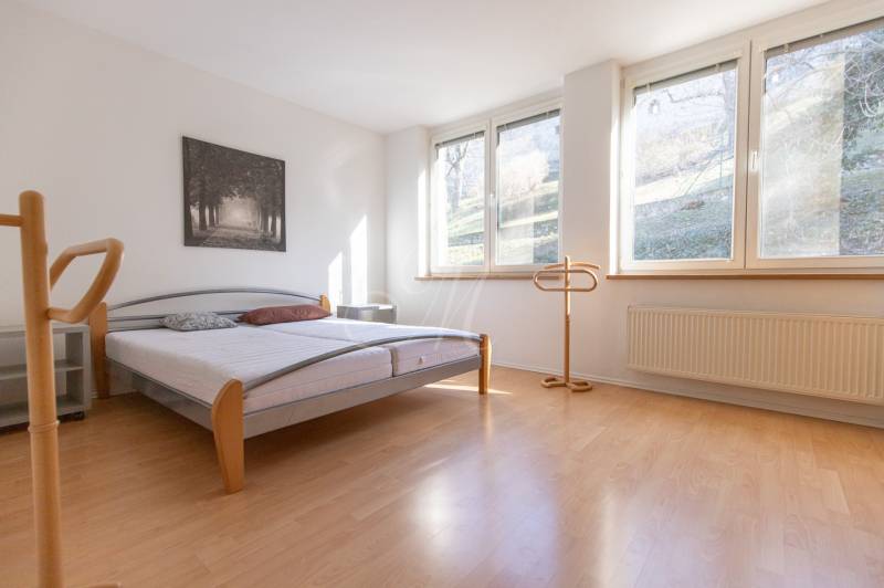 Priestranný 3-izbový byt s loggiou, Staré Mesto - Svetlá spálňa s posteľou a podlahou s dreveným dekorom v 3-izbovom byte.