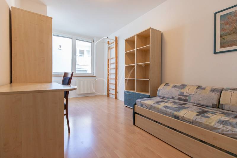 Priestranný 3-izbový byt s loggiou, Staré Mesto - Izba v 3-izbovom byte s rozkladacou pohovkou, regálmi a podlahou s dreveným dekorom.