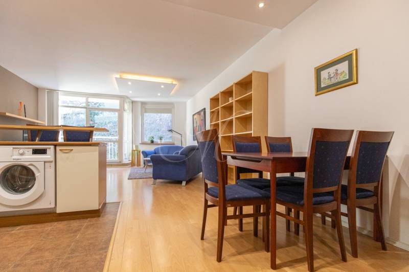 Priestranný 3-izbový byt s loggiou, Staré Mesto - Obývacia izba s podlahou s dreveným dekorom, jedálenským stolom a práčkou v 3-izbovom byte.