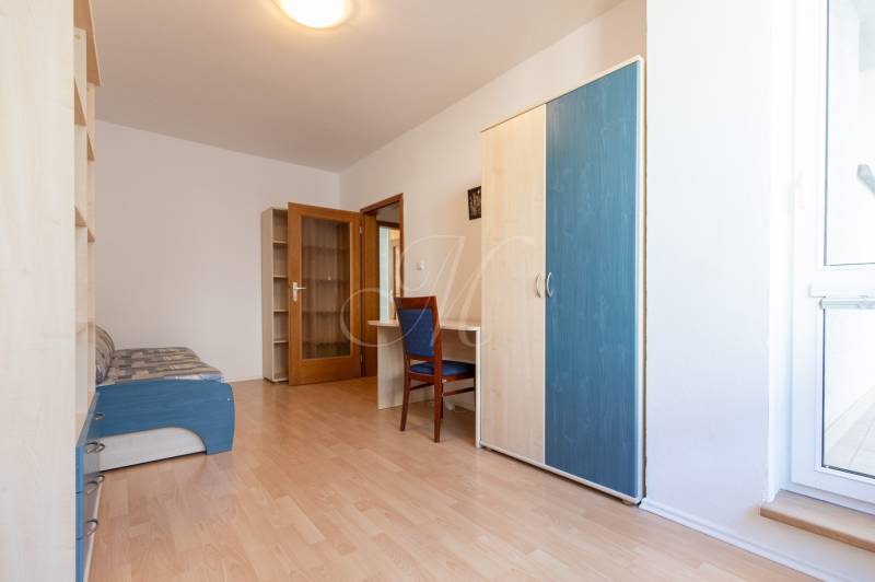 Priestranný 3-izbový byt s loggiou, Staré Mesto - Izba v 3-izbovom byte s podlahou s dreveným dekorom, skriňou a pohovkou.