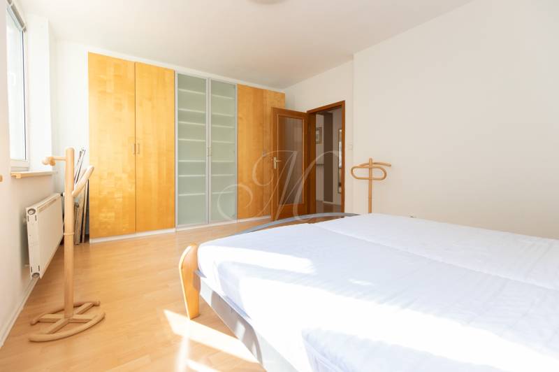 Priestranný 3-izbový byt s loggiou, Staré Mesto - Svetlá spálňa v 3-izbovom byte s podlahou s dreveným dekorom a priestrannou skriňou.