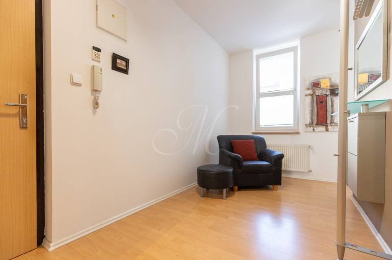 Priestranný 3-izbový byt s loggiou, Staré Mesto - Interiér 3-izbového bytu s kreslom, podlahou s dreveným dekorom a obrazom na stene.