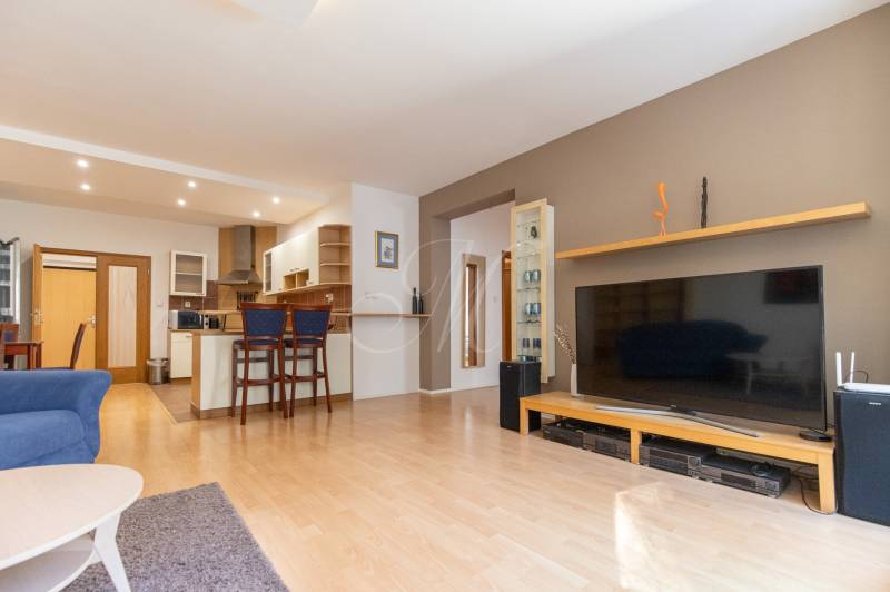 Priestranný 3-izbový byt s loggiou, Staré Mesto - Obývacia izba v 3-izbovom byte so zariadením a podlahou s dreveným dekorom.