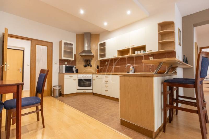 Priestranný 3-izbový byt s loggiou, Staré Mesto - Kuchyňa v 3-izbovom byte s podlahou s dreveným dekorom a barovým pultom.