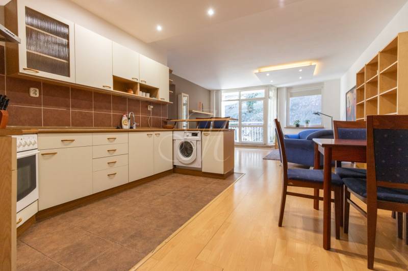 Priestranný 3-izbový byt s loggiou, Staré Mesto - Kuchyňa s podlahou s dreveným dekorom, práčkou a jedálenským stolom v 3-izbovom byte.