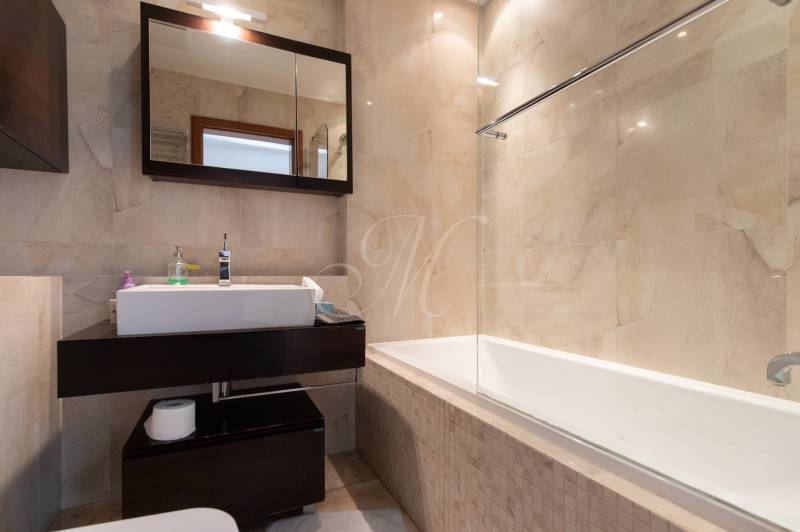 Moderný 2-izbový byt s balkónom, Eurovea - Kúpeľňa s vaňou a tmavým nábytkom v 2-izbovom byte, svetlé obkladačky.