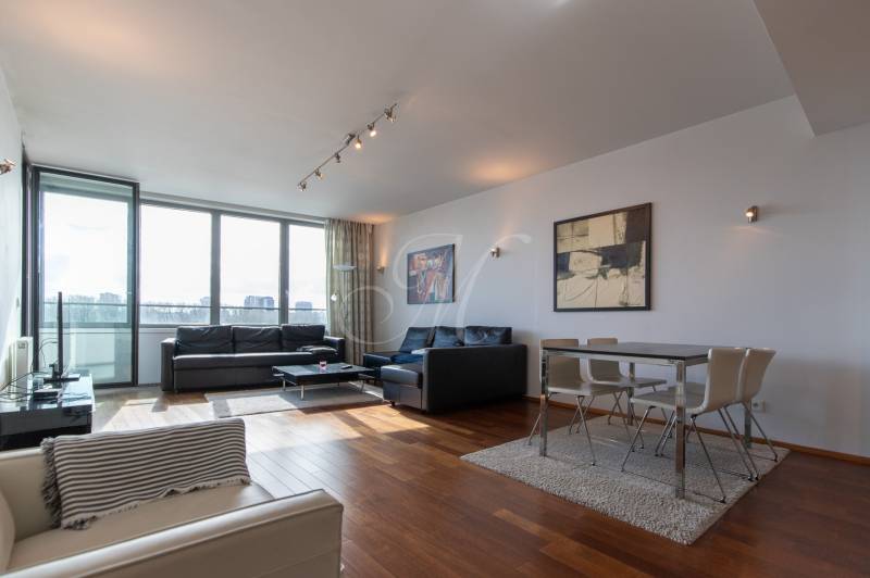 Moderný 2-izbový byt s balkónom, Eurovea - Obývačka s veľkými oknami, podlaha s dreveným dekorom, pohodlný nábytok a jedálenský kút.