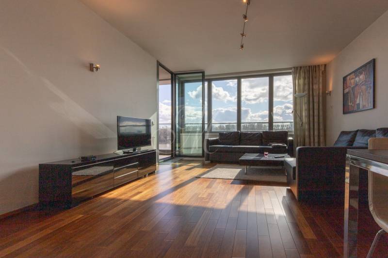 Moderný 2-izbový byt s balkónom, Eurovea - Obývacia izba v 2-izbovom byte s podlahou s dreveným dekorom a veľkými oknami.