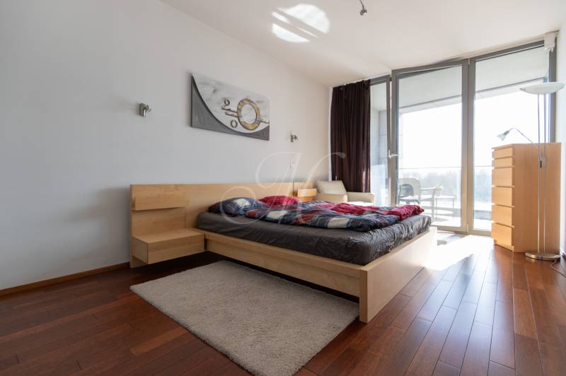 Moderný 2-izbový byt s balkónom, Eurovea - Spálňa v 2-izbovom byte s podlahou s dreveným dekorom a priestrannými oknami.