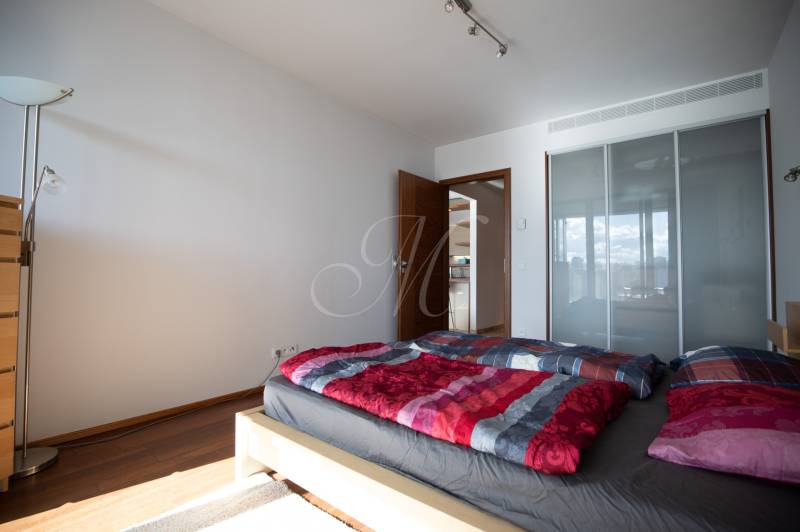 Moderný 2-izbový byt s balkónom, Eurovea - Spálňa v 2-izbovom byte s podlahou s dreveným dekorom, posteľou a skriňou.