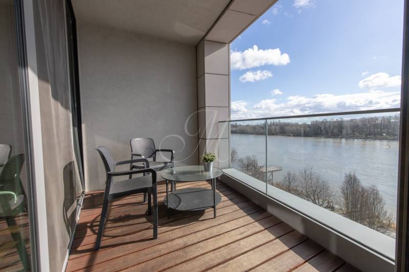 Moderný 2-izbový byt s balkónom, Eurovea - Balkón v 2-izbovom byte s výhľadom na rieku, podlaha s dreveným dekorom.