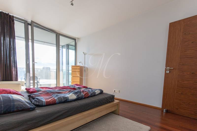 Moderný 2-izbový byt s balkónom, Eurovea - Spálňa v 2-izbovom byte s podlahou s dreveným dekorom a prístupom na balkón.